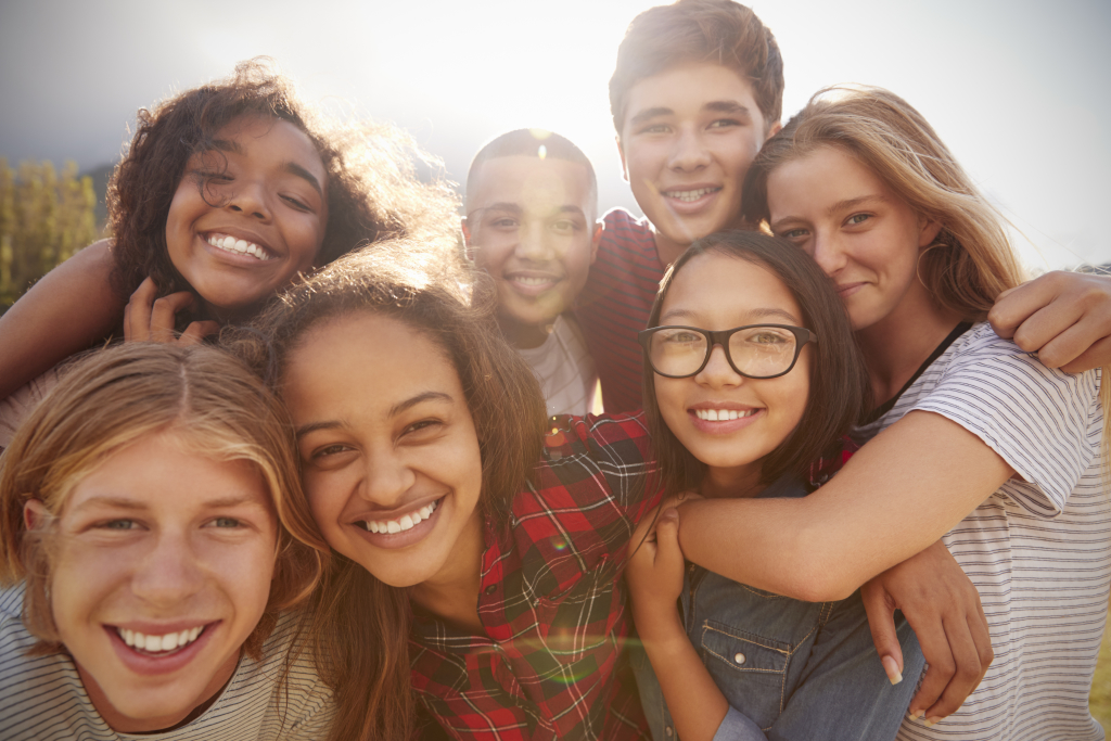 Teenage school friends smiling to camera, close up